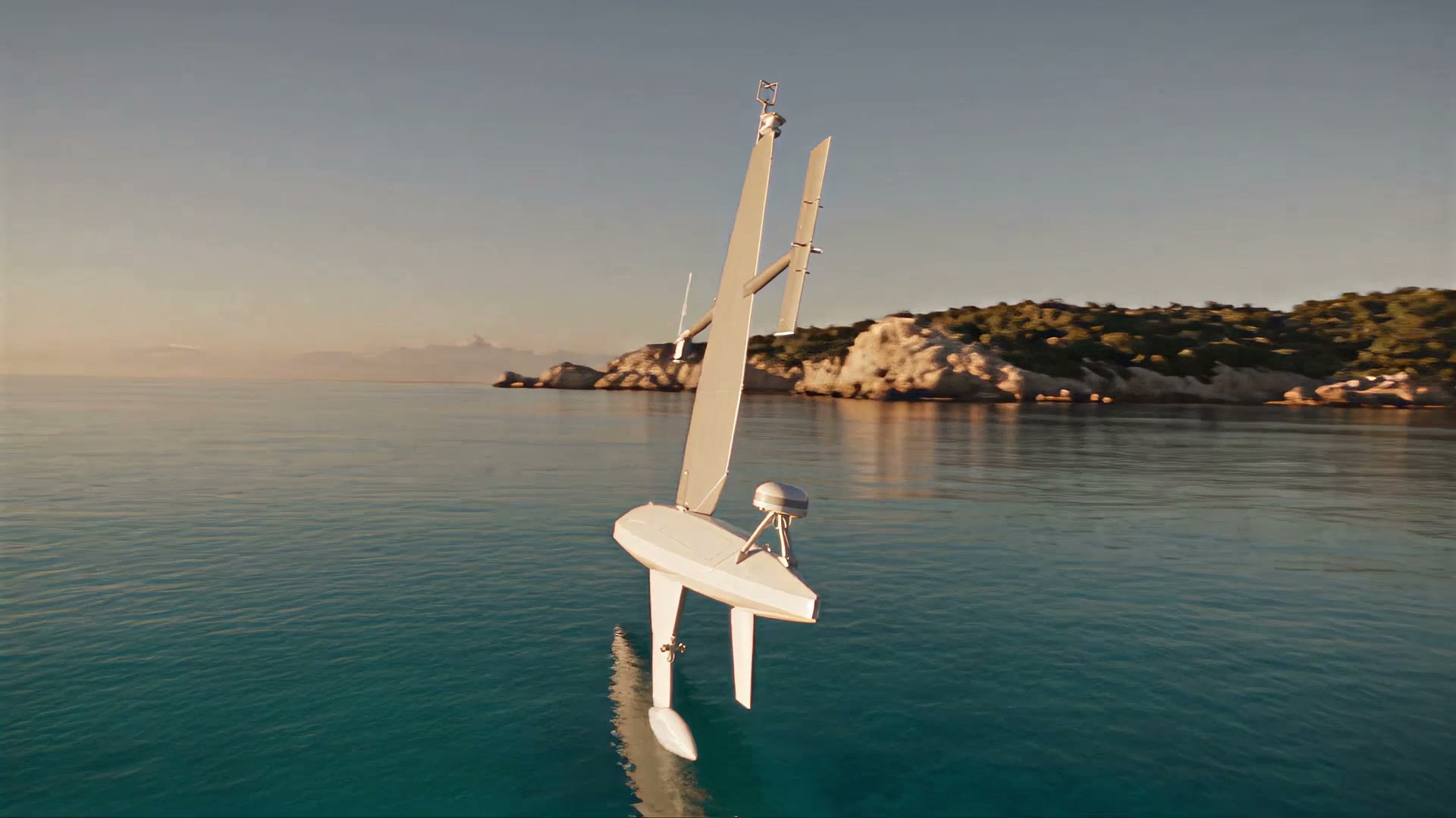 A sail drone under a granite coast in low light, seen from the water